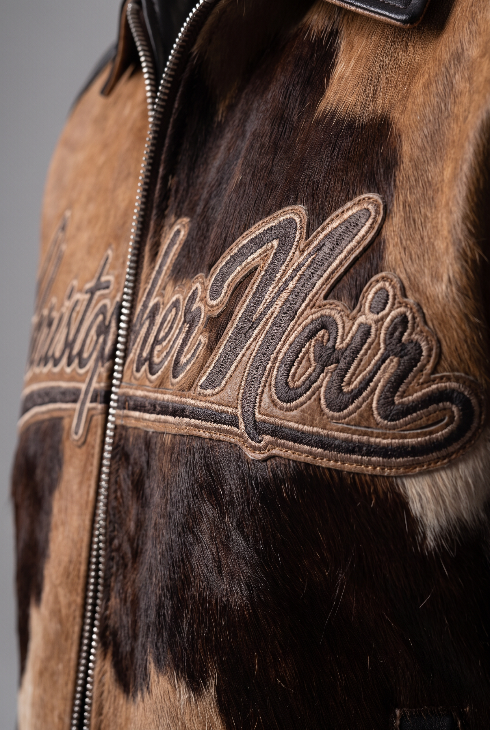 Christopher Noir men's cow hide jacket - close-up detail of hair-on hide, chest embroidery and front zip