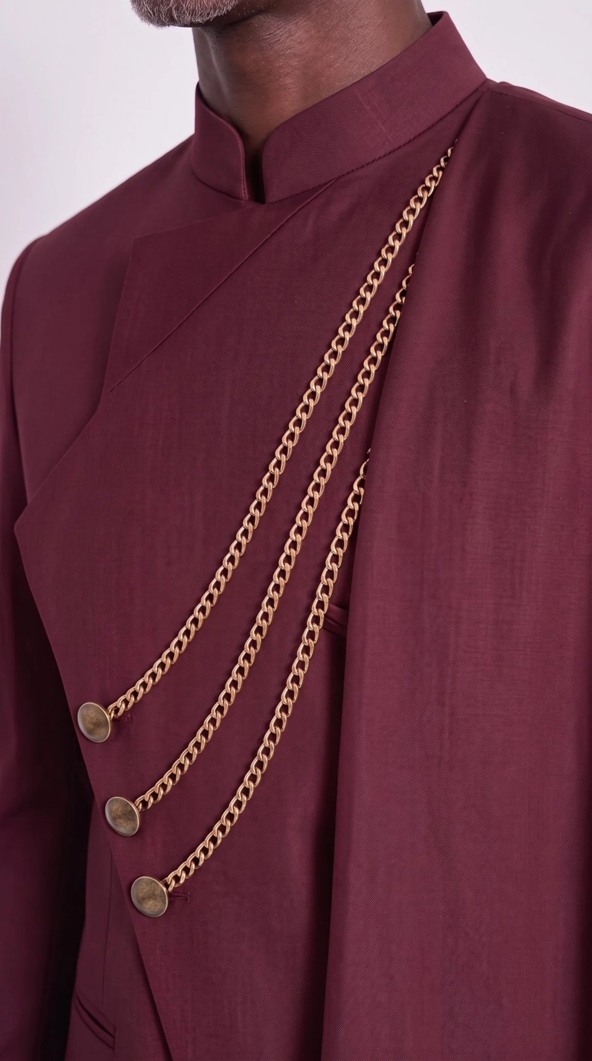 The Noir Chancellor Suit — Burgundy Chain-Drape Suit — gold-tone chain and button close-up, Christopher Noir
