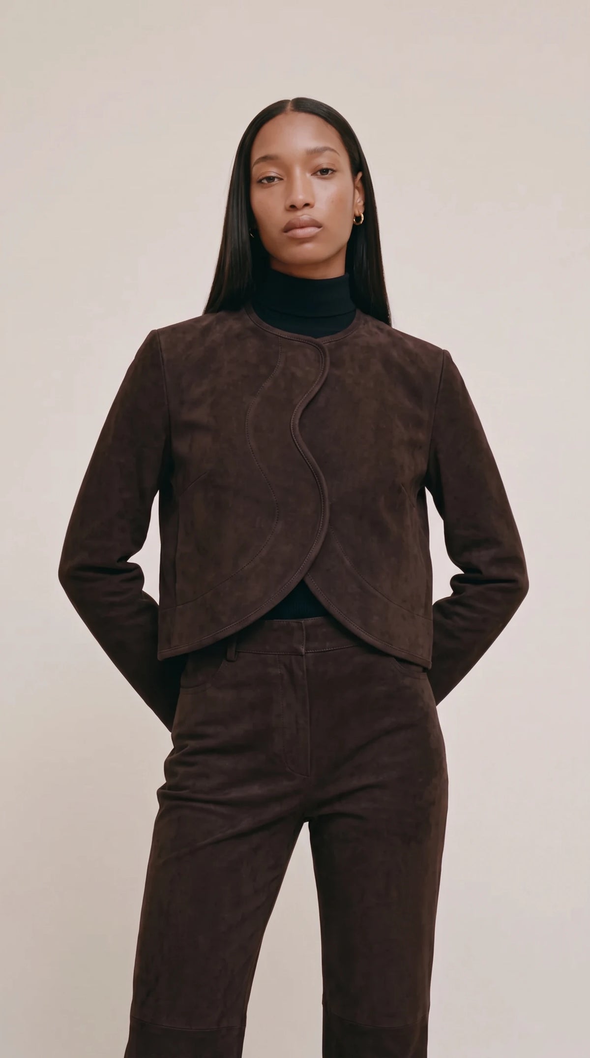 The Noir Hascosay collarless espresso suede jacket with piped S-curve front and rounded cropped hem