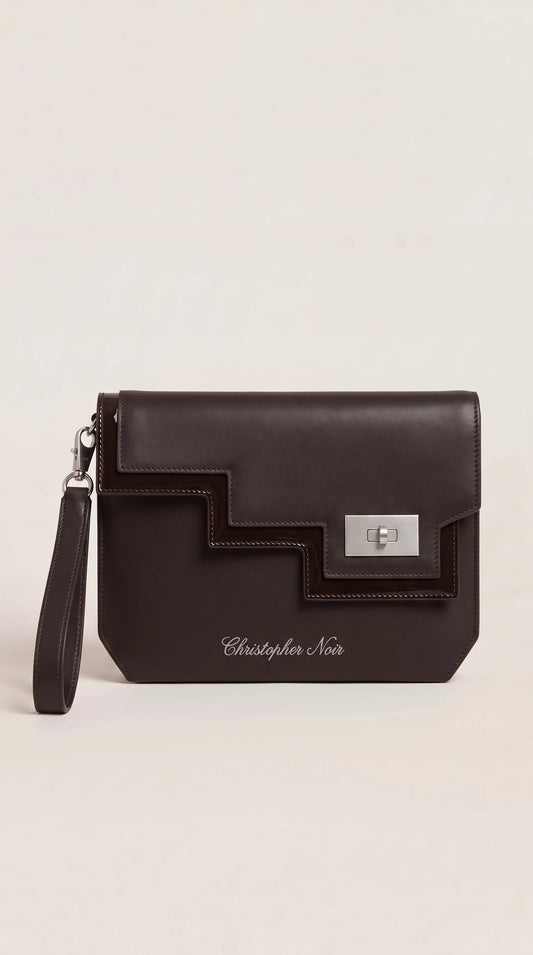 The Noir Rothbury dark brown leather wristlet clutch, front view with stepped geometric panel and silver-tone turn-lock