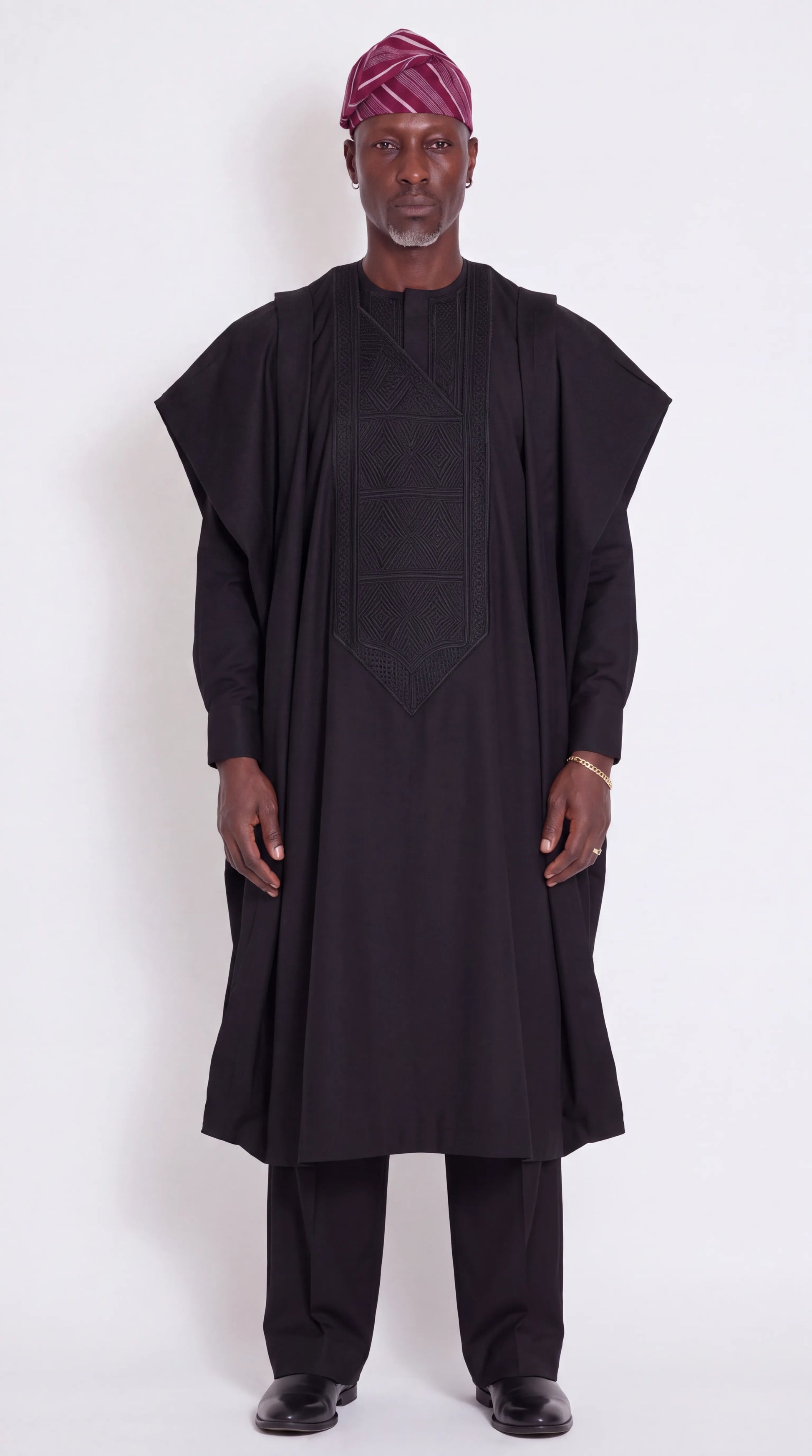 Noir Umbra Agbada — black agbada set, arms folded, three-quarter view