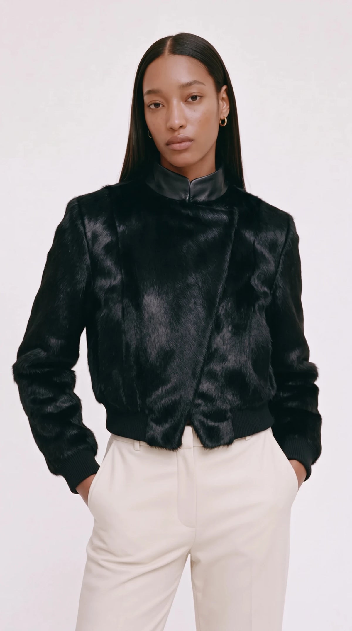 The Noir Unst black hair-on leather bomber jacket with smooth leather stand collar, worn with ivory trousers