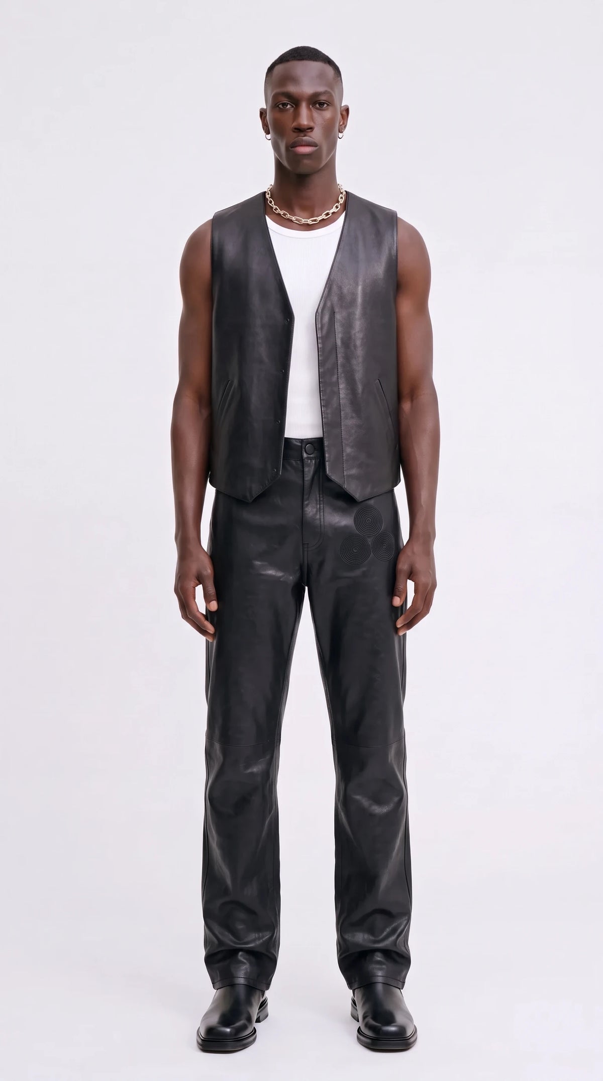 The Noir Yell black leather V-neck waistcoat with pointed front hem, worn over a white vest