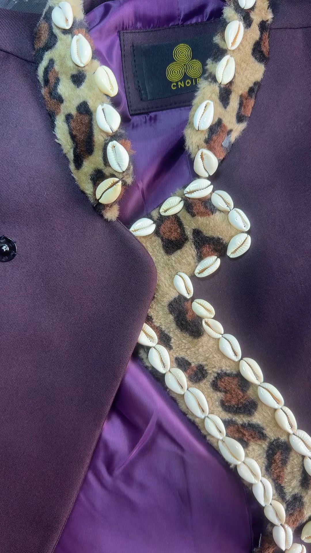 Close-up of a purple garment with a decorative border featuring shells and a leopard print pattern.